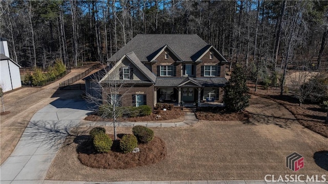 craftsman-style home featuring covered porch, brick siding, and driveway