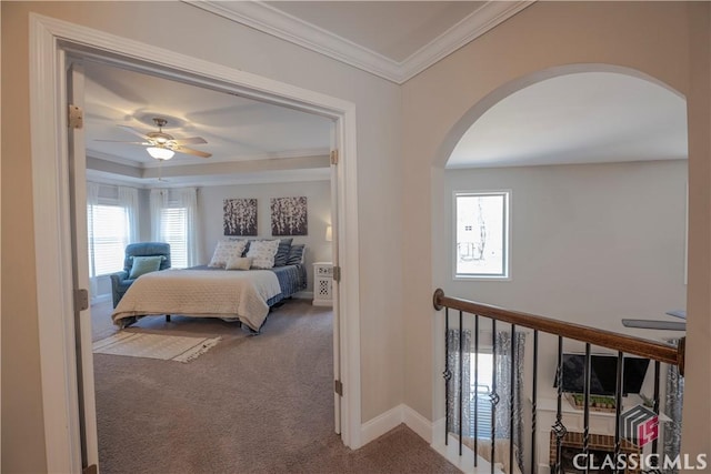 carpeted bedroom with arched walkways, ceiling fan, ornamental molding, and baseboards