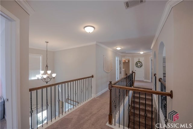 corridor featuring crown molding, a notable chandelier, visible vents, carpet flooring, and an upstairs landing