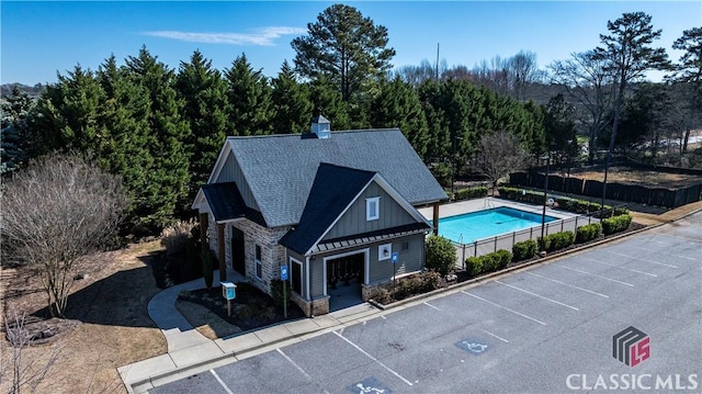 view of building exterior with a fenced in pool, uncovered parking, and fence