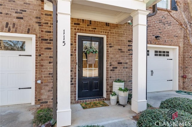 entrance to property featuring a garage and brick siding