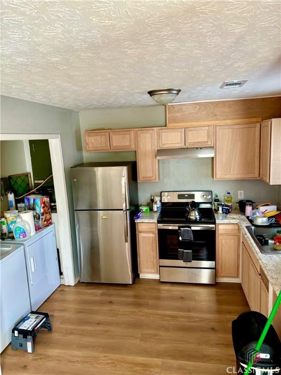 kitchen with visible vents, washer and clothes dryer, stainless steel appliances, light countertops, and under cabinet range hood