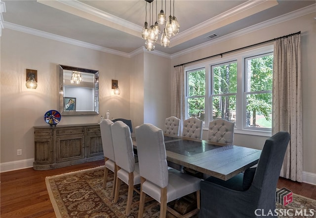 dining space with dark wood-type flooring, a raised ceiling, visible vents, and baseboards