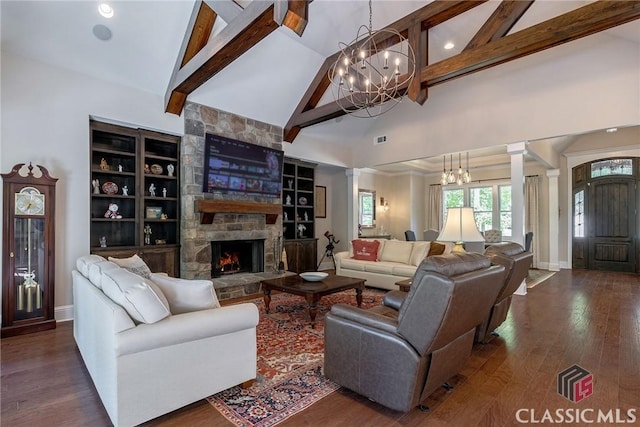 living area featuring ornate columns, a fireplace, dark wood-type flooring, and a notable chandelier