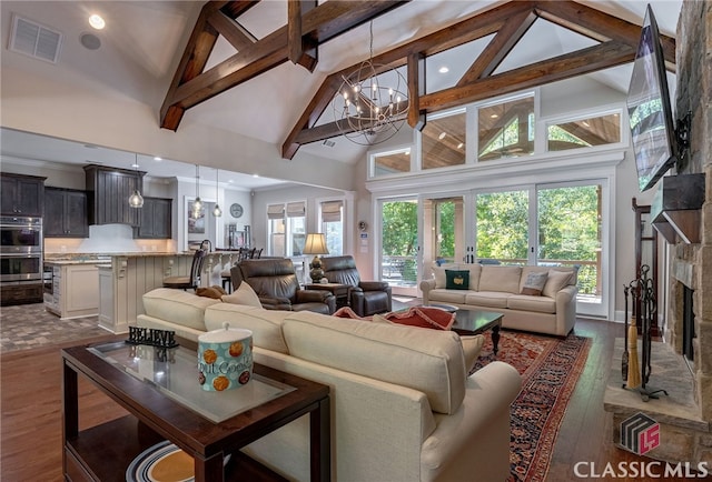 living area featuring visible vents, dark wood-type flooring, a notable chandelier, a stone fireplace, and beam ceiling