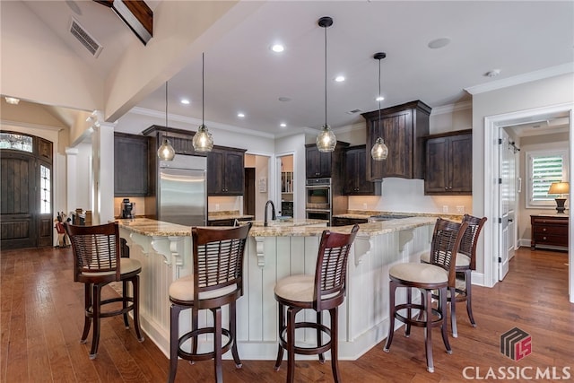 kitchen with stainless steel appliances, visible vents, decorative columns, and dark wood-style floors