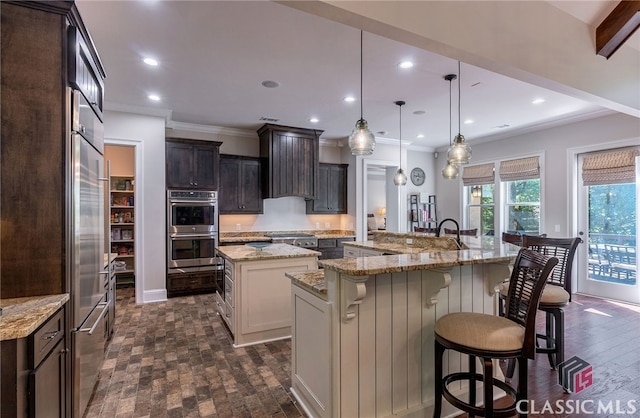 kitchen with a breakfast bar area, stainless steel appliances, dark brown cabinets, a large island with sink, and recessed lighting