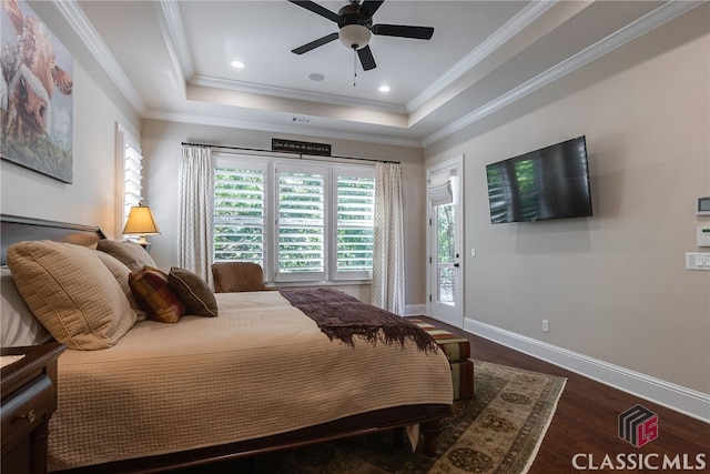 bedroom featuring baseboards, ornamental molding, wood finished floors, access to exterior, and a tray ceiling