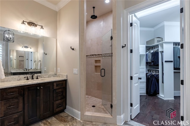 bathroom featuring vanity, baseboards, a spacious closet, ornamental molding, and a shower stall