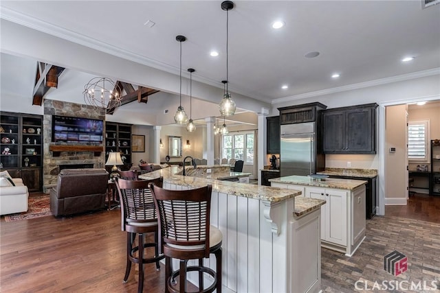 kitchen with a large island, open floor plan, stainless steel built in refrigerator, crown molding, and beam ceiling