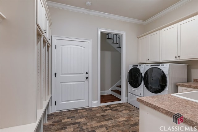 laundry area featuring brick floor, cabinet space, crown molding, and washer and clothes dryer