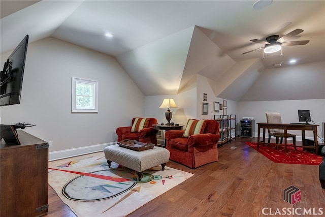 interior space with vaulted ceiling, wood finished floors, a ceiling fan, and baseboards