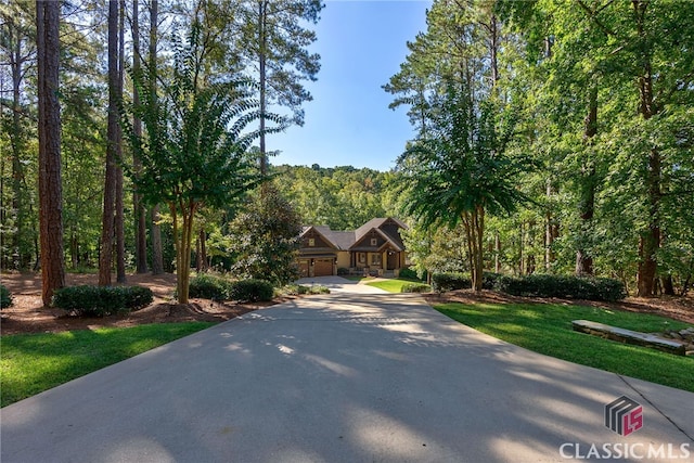 view of front facade featuring a garage, driveway, and a forest view