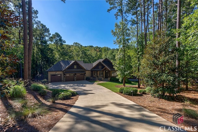 view of front of home featuring concrete driveway, an attached garage, and a wooded view