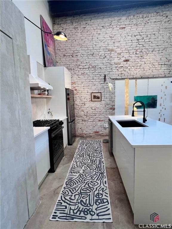 kitchen with concrete floors and wall chimney range hood