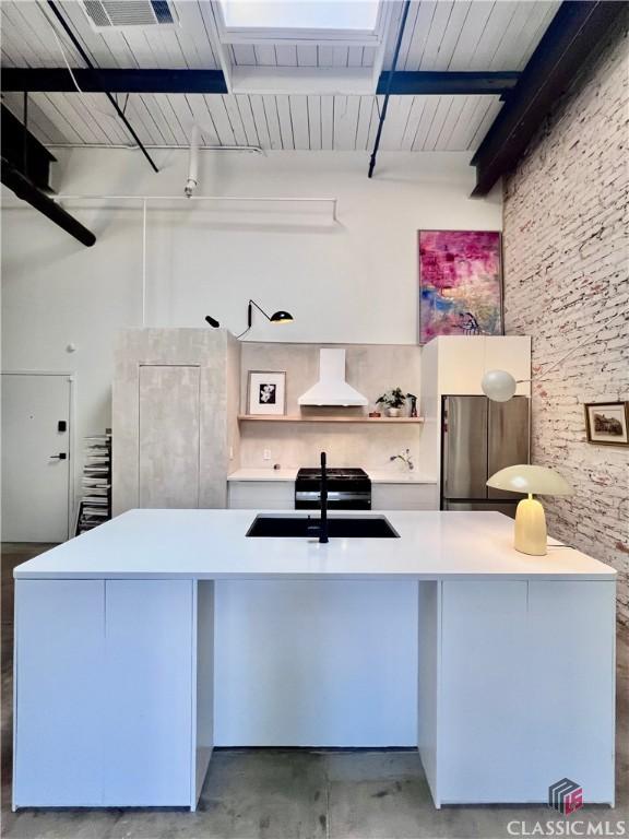 office area with brick wall, concrete floors, and a towering ceiling