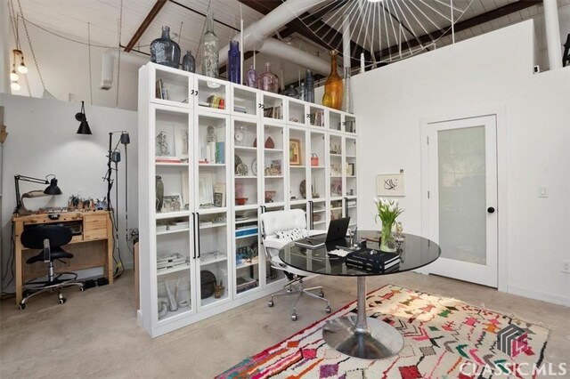 office space with concrete floors, a high ceiling, and baseboards