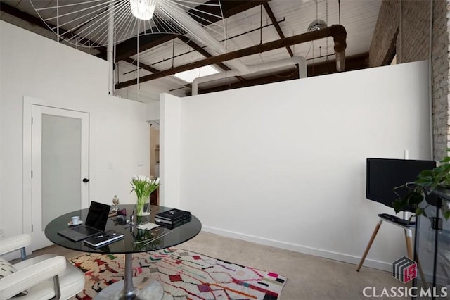 bedroom featuring concrete floors, a high ceiling, and beamed ceiling