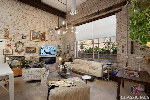 interior space with beamed ceiling, a towering ceiling, and brick wall