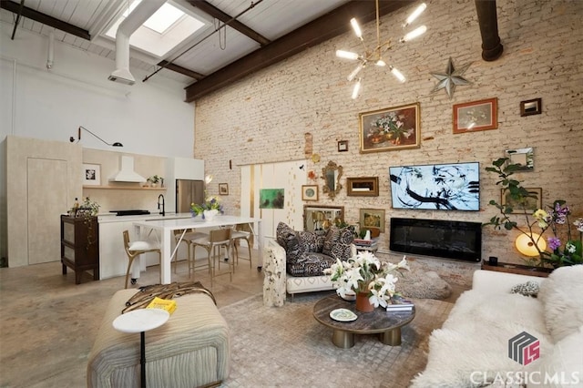 living area with a glass covered fireplace, beam ceiling, a high ceiling, and an inviting chandelier