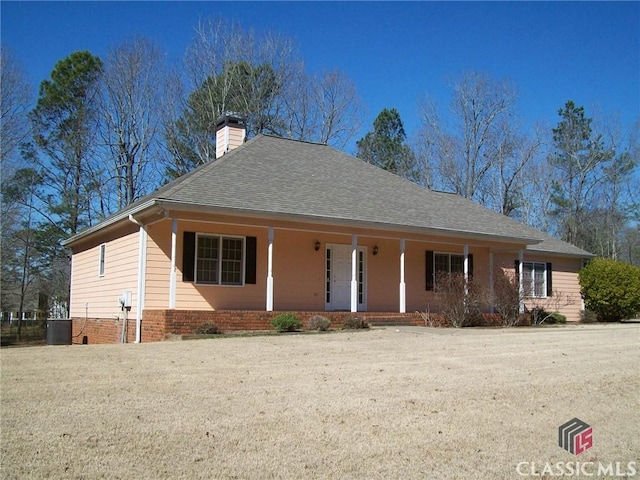 ranch-style house featuring a porch, brick siding, a shingled roof, and a chimney