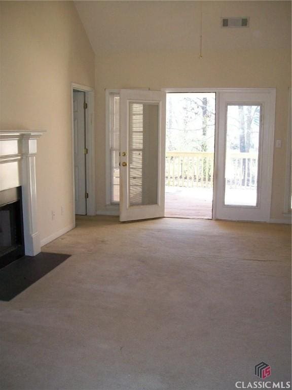 unfurnished living room with high vaulted ceiling, a fireplace with flush hearth, visible vents, and light colored carpet