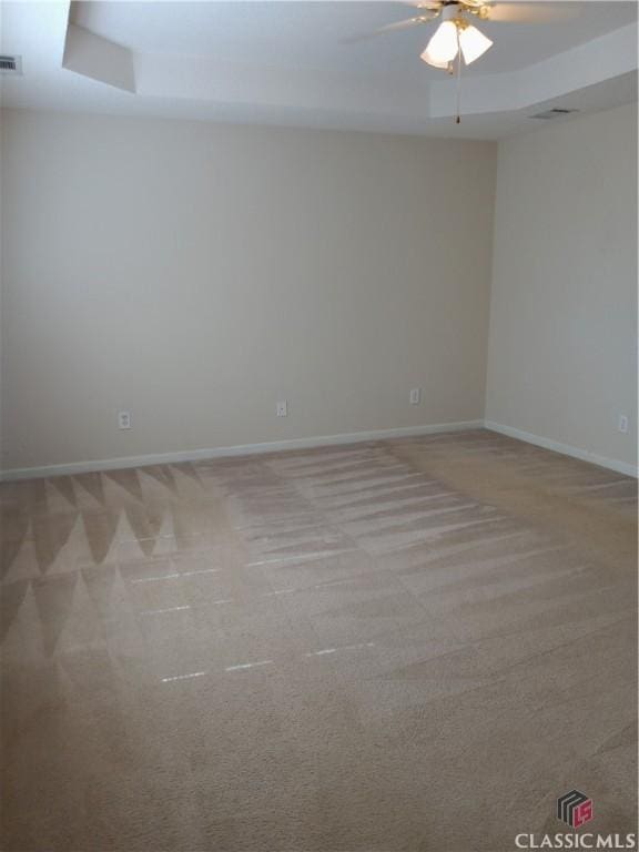 empty room with visible vents, baseboards, a ceiling fan, and light colored carpet