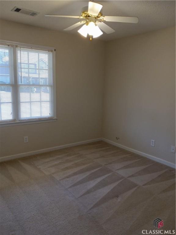 unfurnished room with light carpet, baseboards, visible vents, and a ceiling fan