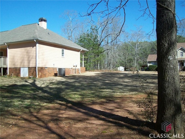 view of property exterior with a chimney, central AC unit, and a lawn