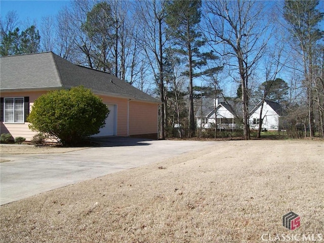 view of property exterior with concrete driveway, roof with shingles, and an attached garage