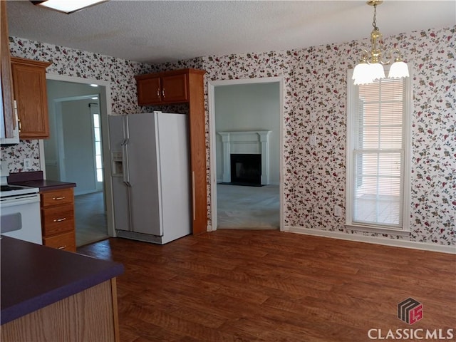 kitchen with dark countertops, white appliances, a textured ceiling, and wallpapered walls