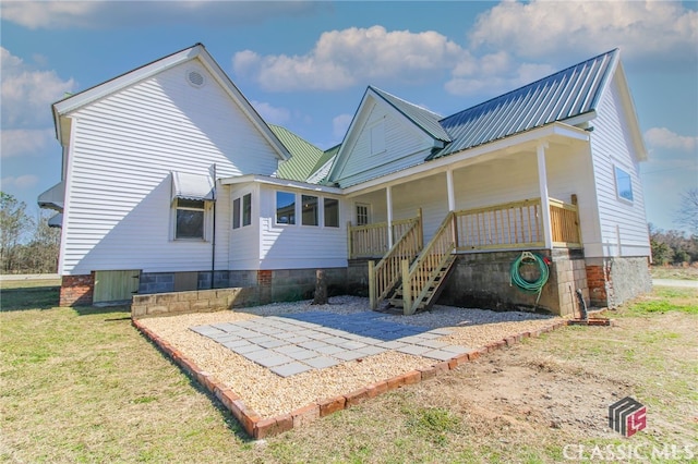 back of house with metal roof and a yard