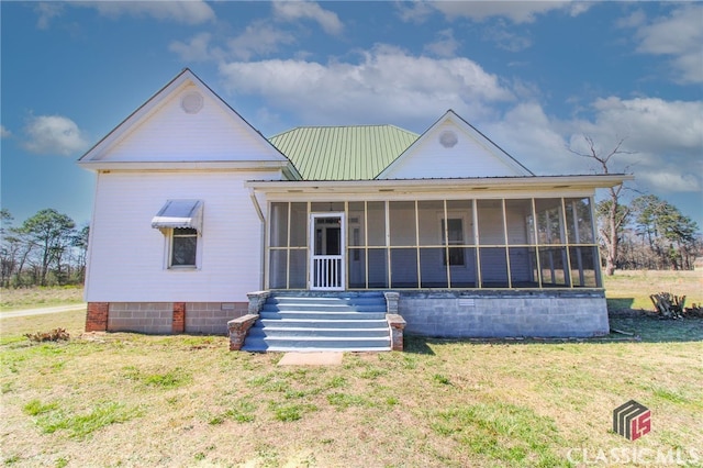 rear view of property featuring a sunroom, metal roof, and a yard