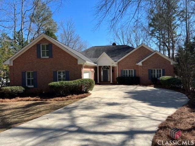 view of front of home with concrete driveway, brick siding, and an attached garage