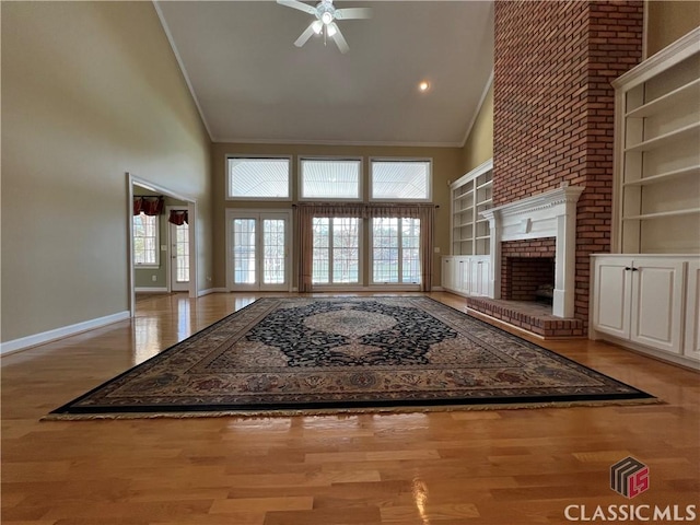 unfurnished living room with high vaulted ceiling, crown molding, and wood finished floors