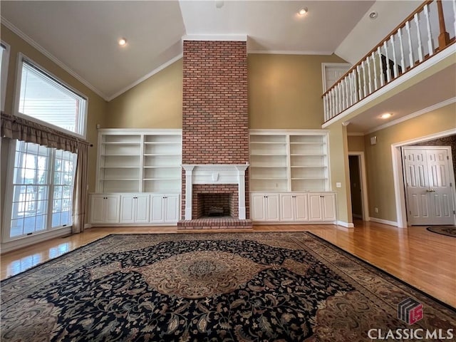 living room with high vaulted ceiling, a fireplace, wood finished floors, baseboards, and crown molding