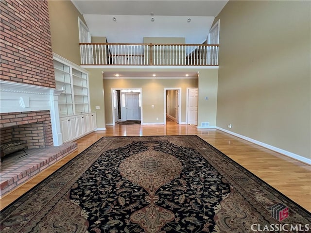 unfurnished living room with wood finished floors, a towering ceiling, and baseboards