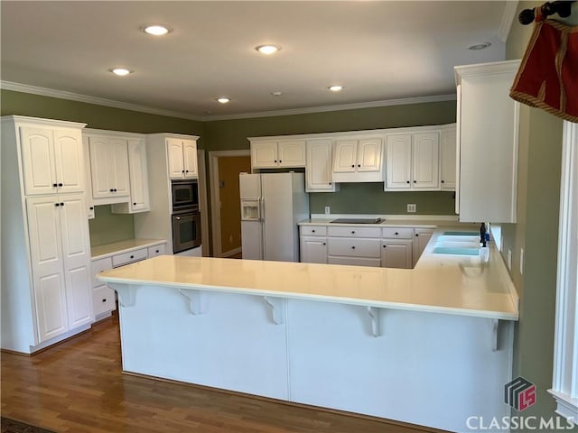 kitchen featuring a breakfast bar area, a peninsula, dark wood-style flooring, a sink, and black appliances