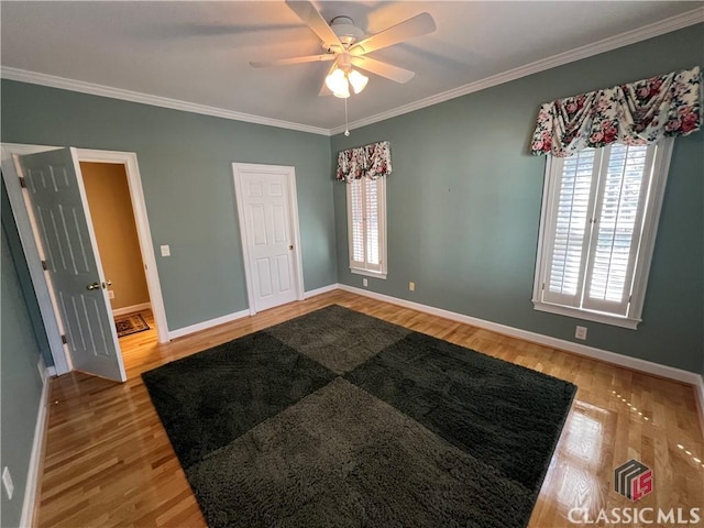 unfurnished room featuring ornamental molding, a ceiling fan, light wood-style flooring, and baseboards