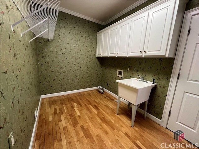 washroom with washer hookup, baseboards, light wood-style floors, ornamental molding, and cabinet space