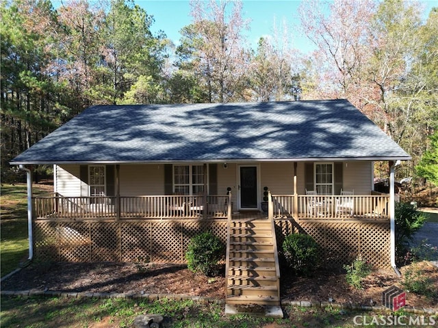 view of front of property featuring covered porch, a shingled roof, and stairs