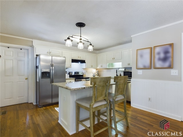 kitchen featuring under cabinet range hood, stainless steel appliances, dark wood-style flooring, a kitchen island, and white cabinets