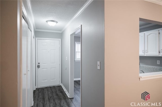 corridor with a textured ceiling, ornamental molding, dark wood-style flooring, and baseboards