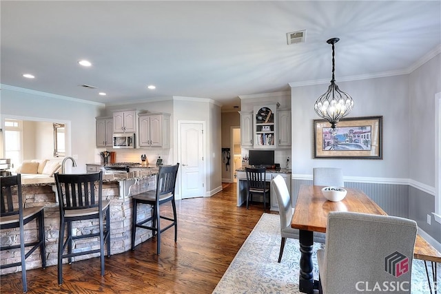 dining area with a chandelier, ornamental molding, dark wood finished floors, and visible vents