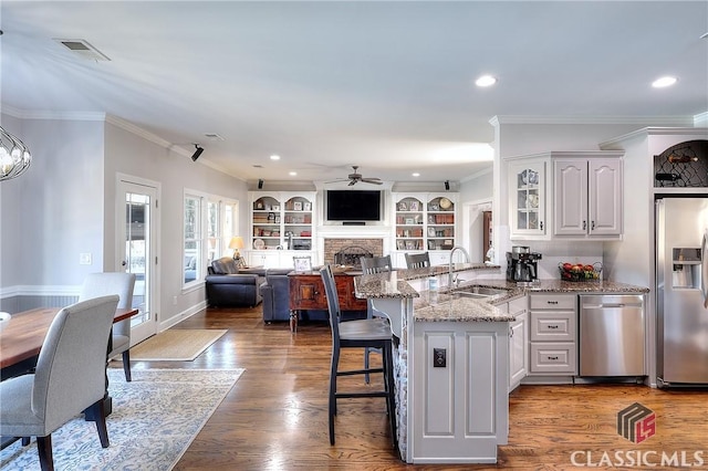 kitchen featuring white cabinets, a peninsula, stainless steel appliances, a kitchen bar, and a sink