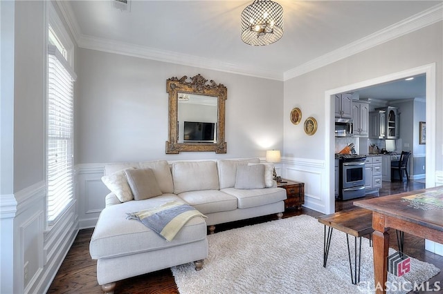 living room with a healthy amount of sunlight, a wainscoted wall, ornamental molding, and dark wood finished floors