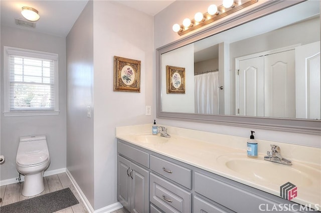 bathroom featuring double vanity, visible vents, toilet, and a sink