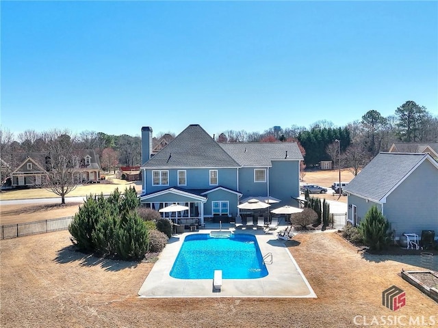 rear view of house featuring a fenced in pool, a patio, and fence