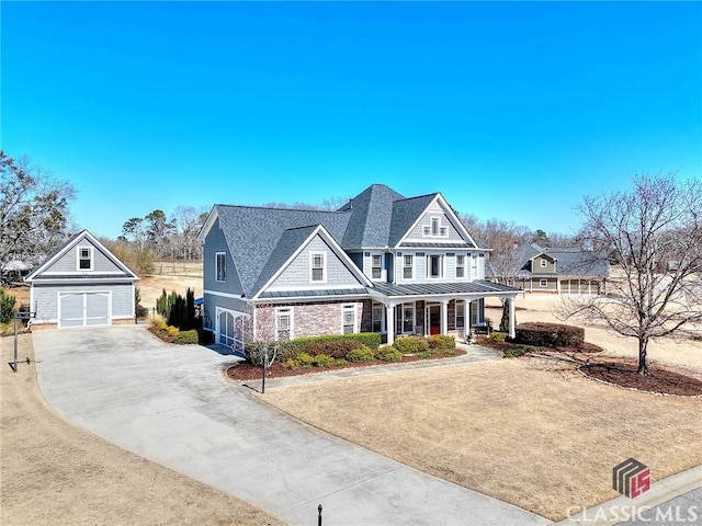 shingle-style home featuring covered porch, a standing seam roof, metal roof, a garage, and an outdoor structure