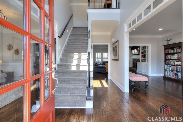 foyer entrance with baseboards, stairway, wood finished floors, crown molding, and a fireplace